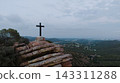 Christian cross on mountain peak with valley view 143311288