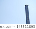 A metal chimney stands tall against a blue sky. 143311893