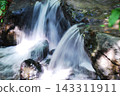 A pristine waterfall flowing through the rocks in the forest. 143311911