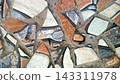 High-quality background of a rustic stone wall texture featuring irregular, interlocking rocks in earth tone shades of brown, terracotta, beige, and gray. The structured surface showcases detailed mas 143311978
