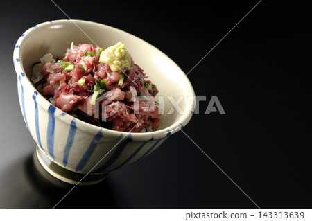 A photo of a tuna bowl against a black background. A photo of a tuna bowl against a black background. 143313639