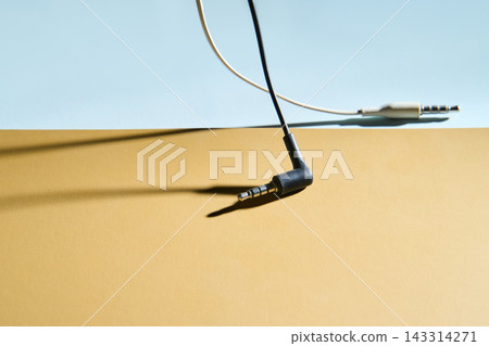 Black Angled Headphone Jack Lying On Two Tone Surface With White Cable And Metal Plug Casting Long Black Angled Headphone Jack Lying On Two Tone Surface With White Cable And Metal Plug Casting Long 143314271