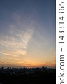Colorful Sunset Sky Glowing Above Dark City Skyline With Wispy Clouds Over Distant Buildings 143314365