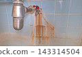 An old metal faucet leaks and leaves rust stains across the blue tiled wall 143314504