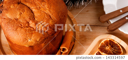 Classic panettone with candied fruit on a decorated table during Christmas celebrations. 143314597