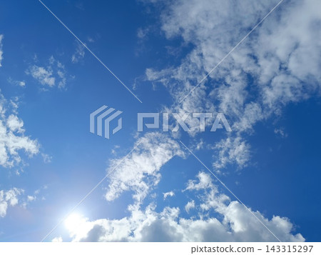 Bright sun shining in a blue sky with white clouds. Sunny summer day background Bright sun shining in a blue sky with white clouds. Sunny summer day background 143315297