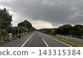 A highway stretches under a sky covered with dark clouds. 143315384