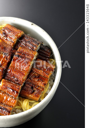 一張鰻魚飯的照片，背景為黑色。 143315648