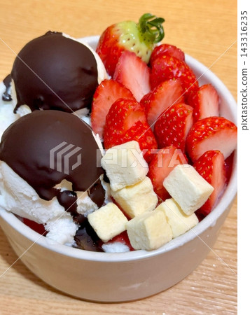 Swirled yogurt ice cream dessert served in a cup, smooth creamy texture with glossy surface, topped with fresh fruit pieces, highlighting its refreshing and inviting appearance in detail 143316235