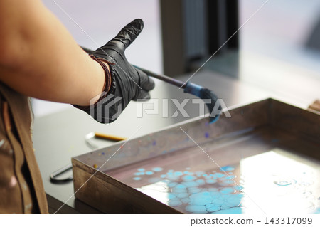 Man creates art using a brush and colored water in a studio setting 143317099