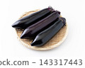 Three fresh long eggplants served on a bamboo basket against a white background. 143317443
