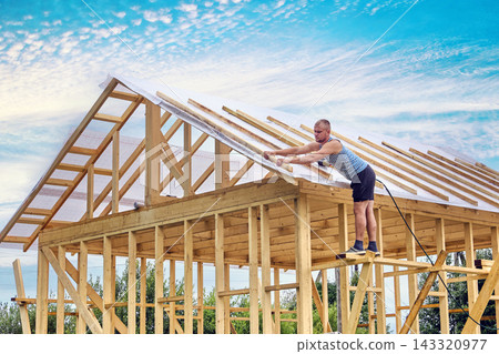 Fastening timber counter battens over roofing membrane for roof ventilation by construction worker. Fastening timber counter battens over roofing membrane for roof ventilation by construction worker. 143320977