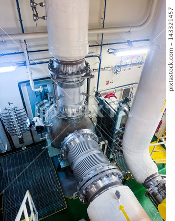 High angle shot of large marine pipelines with expansion bellows joints inside vessel engine room compartment. High angle shot of large marine pipelines with expansion bellows joints inside vessel engine room compartment. 143321457