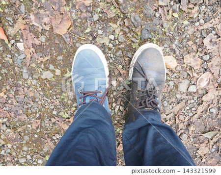 A sneaker with one foot covered in mud after getting stuck in the mud: A comparison of a dirty shoe and a clean shoe. A sneaker with one foot covered in mud after getting stuck in the mud: A comparison of a dirty shoe and a clean shoe. 143321599