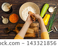 Man's hands add salt from hand mill to bowl of flour. 143321856