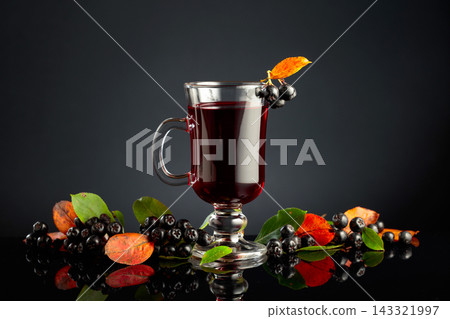 Glass of chokeberry drink and fresh berries with leaves. Glass of chokeberry drink and fresh berries with leaves. 143321997