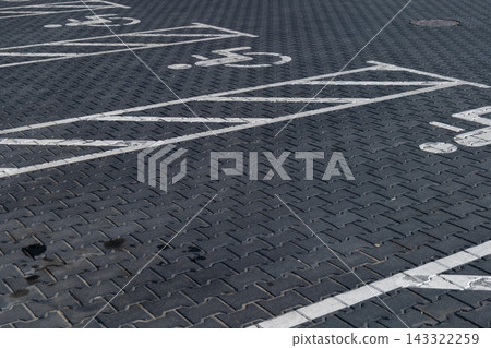 A clearly marked parking space for disabled individuals is visible on the ground in a parking lot during daylight hours A clearly marked parking space for disabled individuals is visible on the ground in a parking lot during daylight hours 143322259