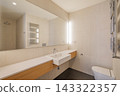 Modern bathroom with a sleek design. Features a large mirror, minimalist sink, wooden cabinetry, and contemporary lighting. Neutral color palette enhances spaciousness. 143322357