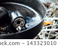 Used oil filter and drain plug sitting in an oil drain pan after an oil change 143323010