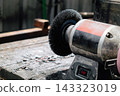 Bench grinder sitting on a workbench in a workshop, ready for metalworking 143323019
