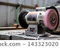 Bench grinder sitting on a workbench in a workshop, ready for metalworking 143323020