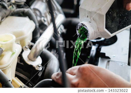 Mechanic pouring green coolant liquid into car engine Mechanic pouring green coolant liquid into car engine 143323022