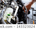 Mechanic hand performing maintenance by checking coolant reservoir in a car engine 143323024