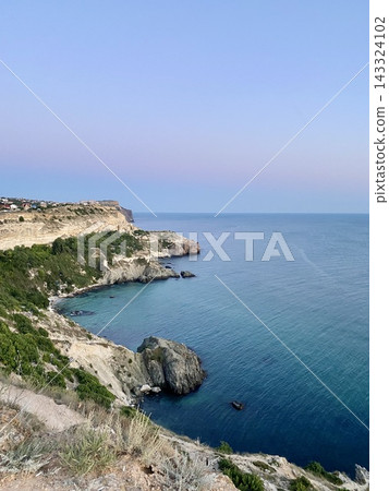 Expansive Black Sea coastline stretches past rugged cliffs under soft pastel sky. Expansive Black Sea coastline stretches past rugged cliffs under soft pastel sky. 143324102