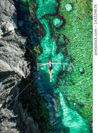 Aerial top view of a girl lying in the water on rocky the Angels Billabong in Nusa Penida island Aerial top view of a girl lying in the water on rocky the Angels Billabong in Nusa Penida island 143324676