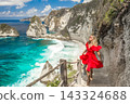 Woman wearing a red dress on standing on the stairs leading down at Diamond beach in Nusa Penida 143324688