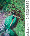 Amazing natural aquarium in coastal rocks with girl lying in the water on Angels Billabong in Nusa 143324689