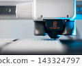 Extreme macro shot of 3D printer nozzle printing white plastic object 143324797