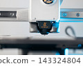 Close up of 3D printer nozzle with caution hot warning sign 143324804