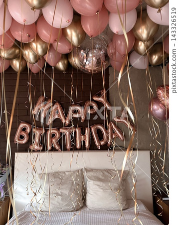 Metallic birthday letters and balloons decorate bright bedroom in warm sunlight. Metallic birthday letters and balloons decorate bright bedroom in warm sunlight. 143326519
