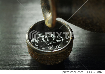 將熱清酒倒入杯中。 143326887