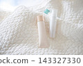 White quilted fabric and skincare products. Natural light. 143327330