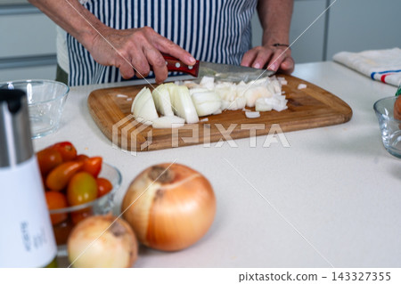 Focused preparation chopping fresh onions for empanada filling Focused preparation chopping fresh onions for empanada filling 143327355