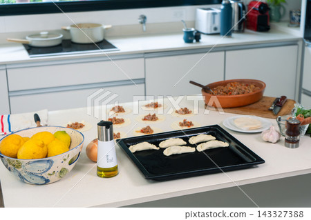 Empanada preparation in progress with golden lemons meat filling and dough ready to bake Empanada preparation in progress with golden lemons meat filling and dough ready to bake 143327388