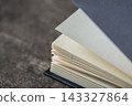 Open book with textured pages and dark cover, turning a new page, symbolizing learning and discovery 143327864