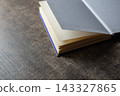 Open book with blank pages on a dark wooden table, ready for writing, learning, or storytelling 143327865