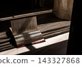 Open book lying on a wooden floor, catching warm sunlight stripes through window blinds, creating a tranquil atmosphere 143327868