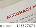 Macro view of accuracy word printed in red on a white paper page, showing detail of text typography 143327874