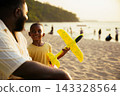 Black father sitting with son on beach talking during sunset 143328564