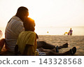 Black father sitting with son on beach talking during sunset 143328568