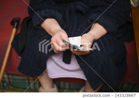 Senior woman counting money in hands with visible Ukrainian hryvnia banknotes, 143328667