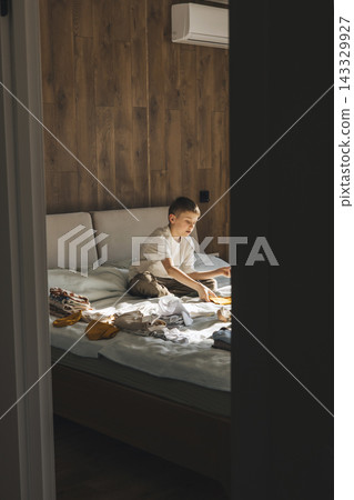 Older Brother Preparing Baby Clothes for New Sibling at Home 143329927