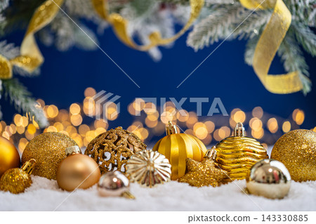 Gold Christmas Ornaments with Ribbon on Snow, Blue Backdrop 143330885