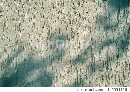 Abstract light and shadow pattern on a beige textured stucco wall Abstract light and shadow pattern on a beige textured stucco wall 143331116