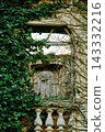 arched window opening broken, wooden door interior visible, stone balusters balustrade, ivy surrounding frame 143332216