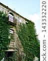 diagonal building angle view, multiple balconies stacked, iron railing upper level, stone balusters lower 143332220